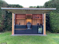 an outdoor bar in the shape of a shed with its doors open and shelves full of bottles