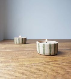 two striped tea lights sitting on top of a wooden table next to another candle holder