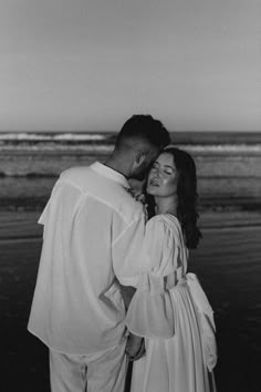 a man and woman standing next to each other near the ocean