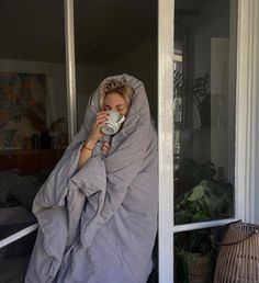 a woman wrapped in a blanket drinking from a cup