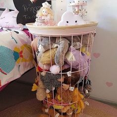 there is a basket full of stuffed animals on the table in front of a bed