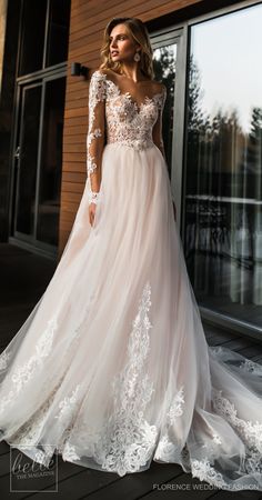 a woman standing in front of a window wearing a dress with long sleeves and lace detailing