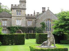 a dog statue sitting on top of a lush green field next to a tall building