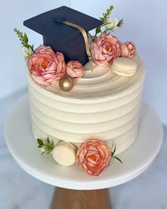 a white cake with flowers and a graduation cap on top