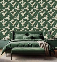 a bed with green sheets and pillows in front of a wallpapered background that has white birds on it