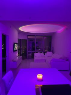 a living room filled with white furniture and purple lighting