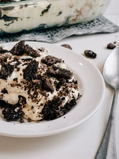 a white plate topped with oreo cookies and cream dessert next to a fork on a table