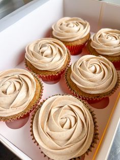 six cupcakes with frosting in a white box