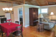 a living room filled with furniture and a red table cloth on top of a wooden floor