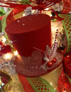 a red hat sitting on top of a table covered in christmas decorations and ribbons,