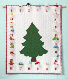 a quilted christmas tree hanging on the wall with numbers around it and santa's helper