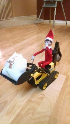 an elf is riding a toy bulldozer on the floor