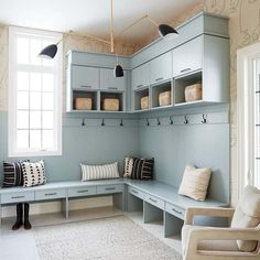 a room that has some blue cabinets and white flooring with pillows on the bench