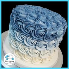 a blue and white frosted cake with roses on it's top is sitting on a plate