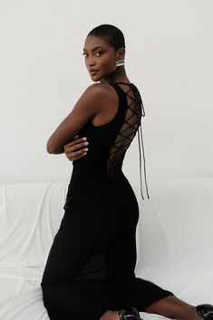 a woman in a black dress sitting on a white couch