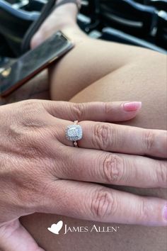 a close up of a person's hand with a diamond ring on her finger