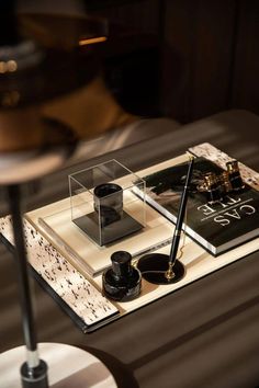 a desk with a pen, inkwell and other items on it next to a lamp