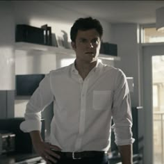 a man in white shirt and black pants standing next to shelves with books on it