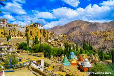 an aerial view of a village in the mountains with colorful buildings and trees around it