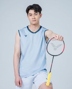 a young man holding a tennis racquet on top of a white floor next to a gray wall