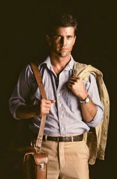 a man is holding his luggage and posing for the camera with it's belt around his neck