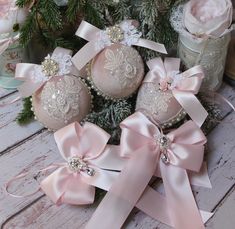 some ornaments are sitting on a table with pink ribbons and bows around them, as well as flowers