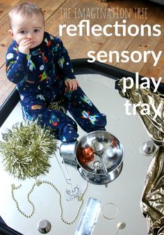 a baby sitting on top of a metal tray