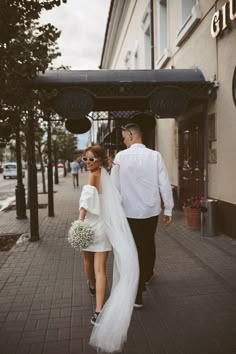 a bride and groom walking down the street