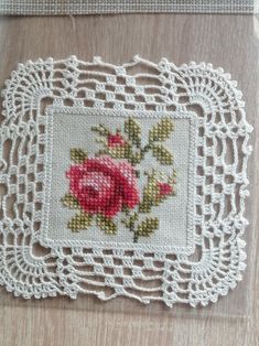 an embroidered doily with a pink rose on it