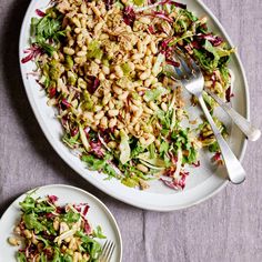 two plates with salad and silverware next to each other