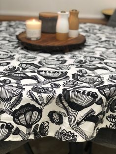 a black and white table cloth with flowers on it, next to two lit candles