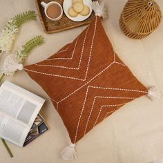 a brown pillow sitting on top of a bed next to a cup of coffee and an open book