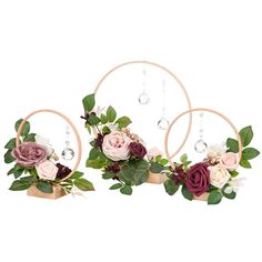 three flowers are hanging from the hoop with beads and leaves on it, along with greenery