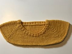 a knitted yellow sweater on a white surface