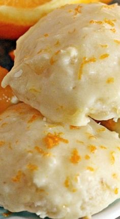 two scoops of ice cream sitting on top of a white plate next to orange slices