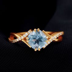 a gold ring with an aqua blue topazte and white diamonds on the sides