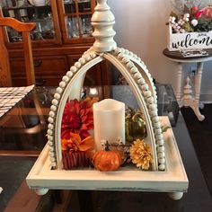 a candle and some flowers are on a table in front of a sign that says welcome