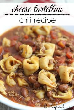 a white bowl filled with pasta and cheese tortellini chili recipe on top of a wooden table