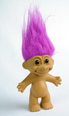 a toy troll with purple hair on it's head and eyes, standing in front of a white background