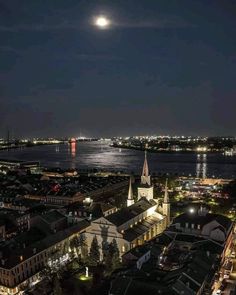 a full moon is seen over the city lights and buildings at night in this aerial photo