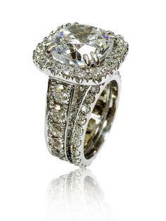 an engagement ring set with a cushion cut diamond surrounded by round brilliant pave diamonds