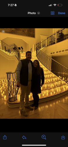 two people standing next to each other in front of stairs with lit candles on them