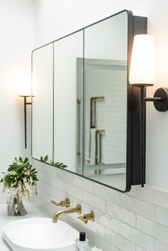 a white bathroom sink sitting under a large mirror