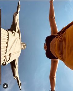 a woman standing next to a statue in front of a blue sky and white clouds