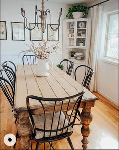 a wooden table with chairs around it and a vase filled with flowers on the table