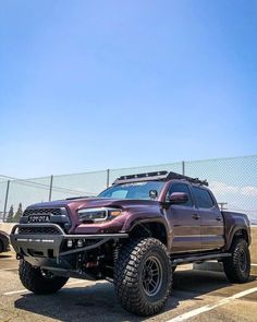 a purple toyota truck parked in a parking lot next to a chain link fence on a clear day