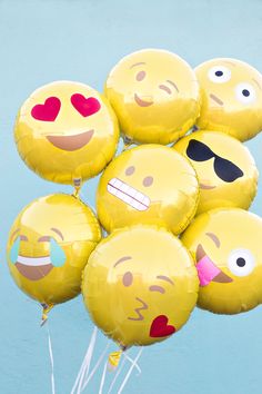 a bunch of smiley face balloons floating in the air with one balloon sticking out of it's mouth