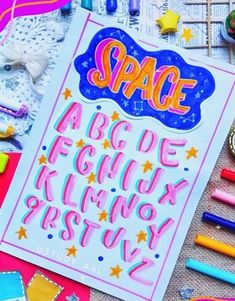 an open notebook with the words space on it and some crayons around it