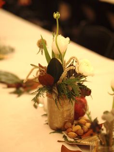 flowers and nuts are arranged in a vase on a table