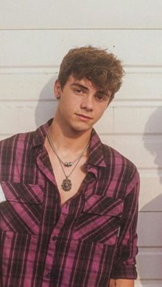 a young man standing in front of a white wall